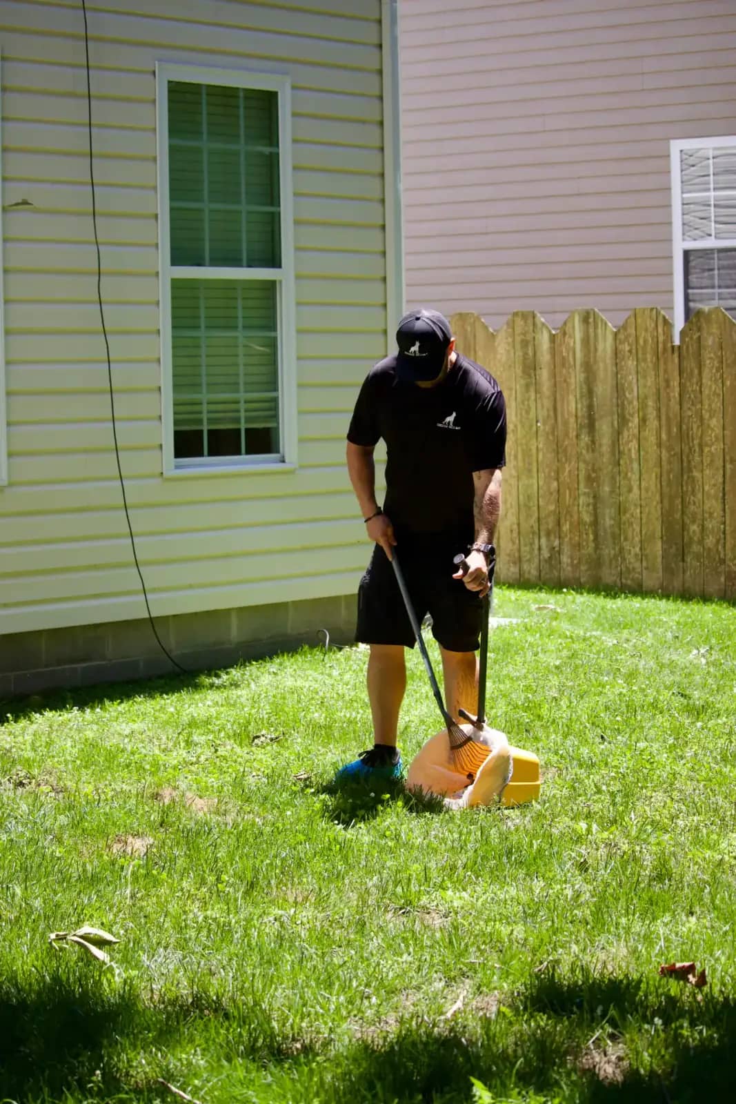Doggy Scoop technician cleaning pet waste from a fenced backyard