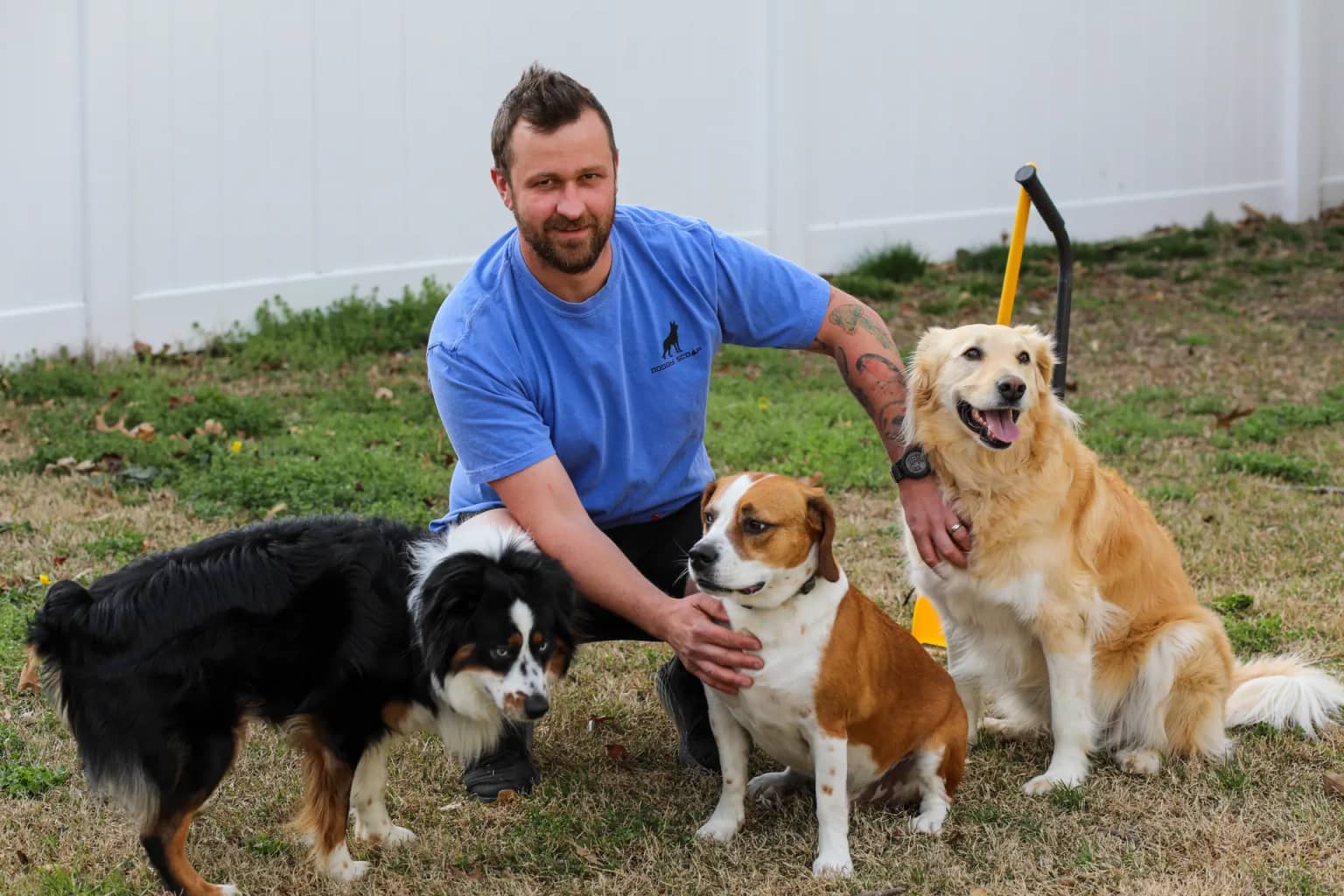 Doggy Scoop team member with three dogs in a backyard