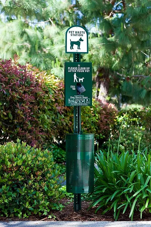 Stocked pet waste station service for shared spaces Complete pet waste station with stocked bags and receptacle in maintained landscaping